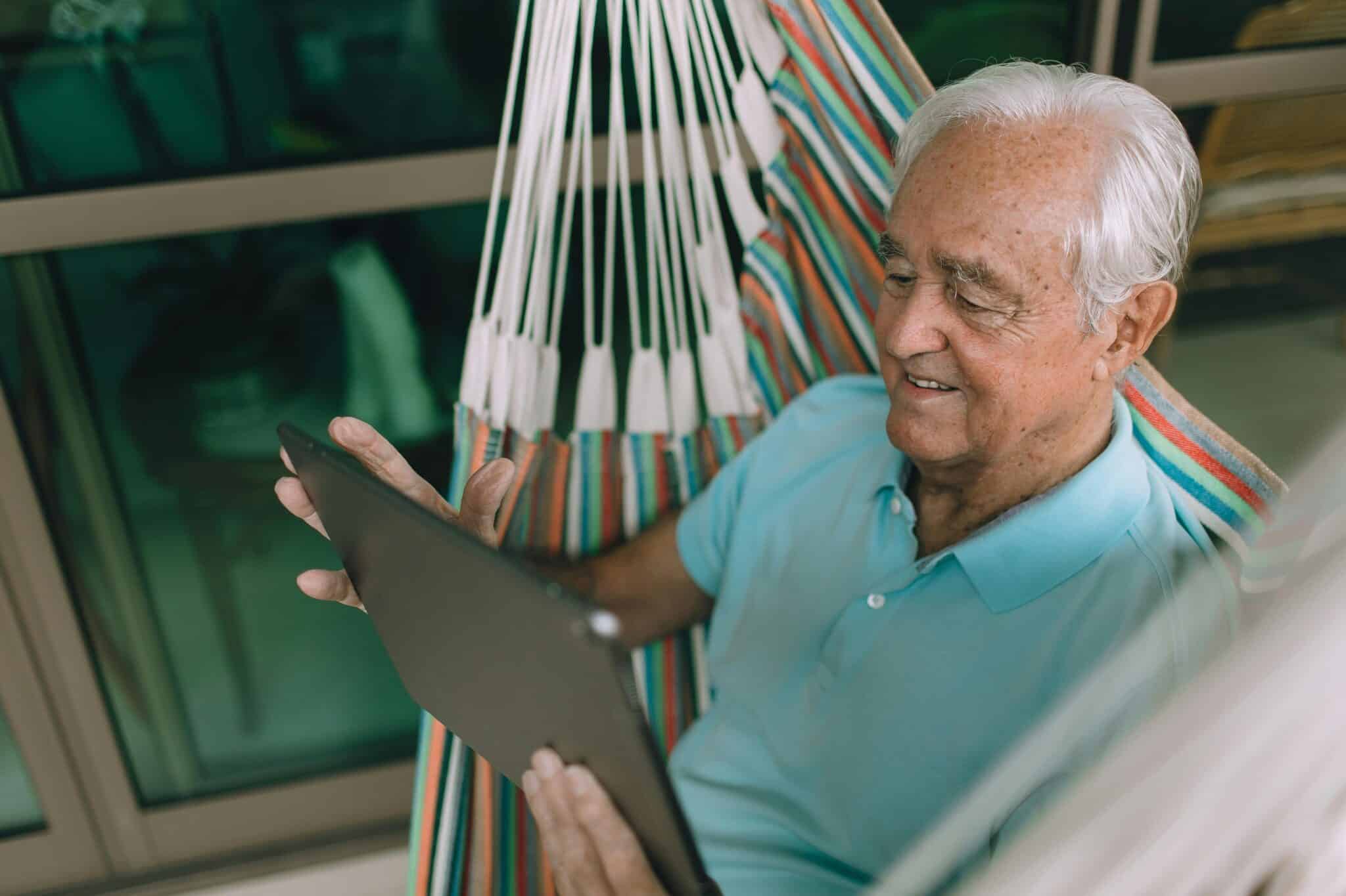 Senior man on hammock using a tablet