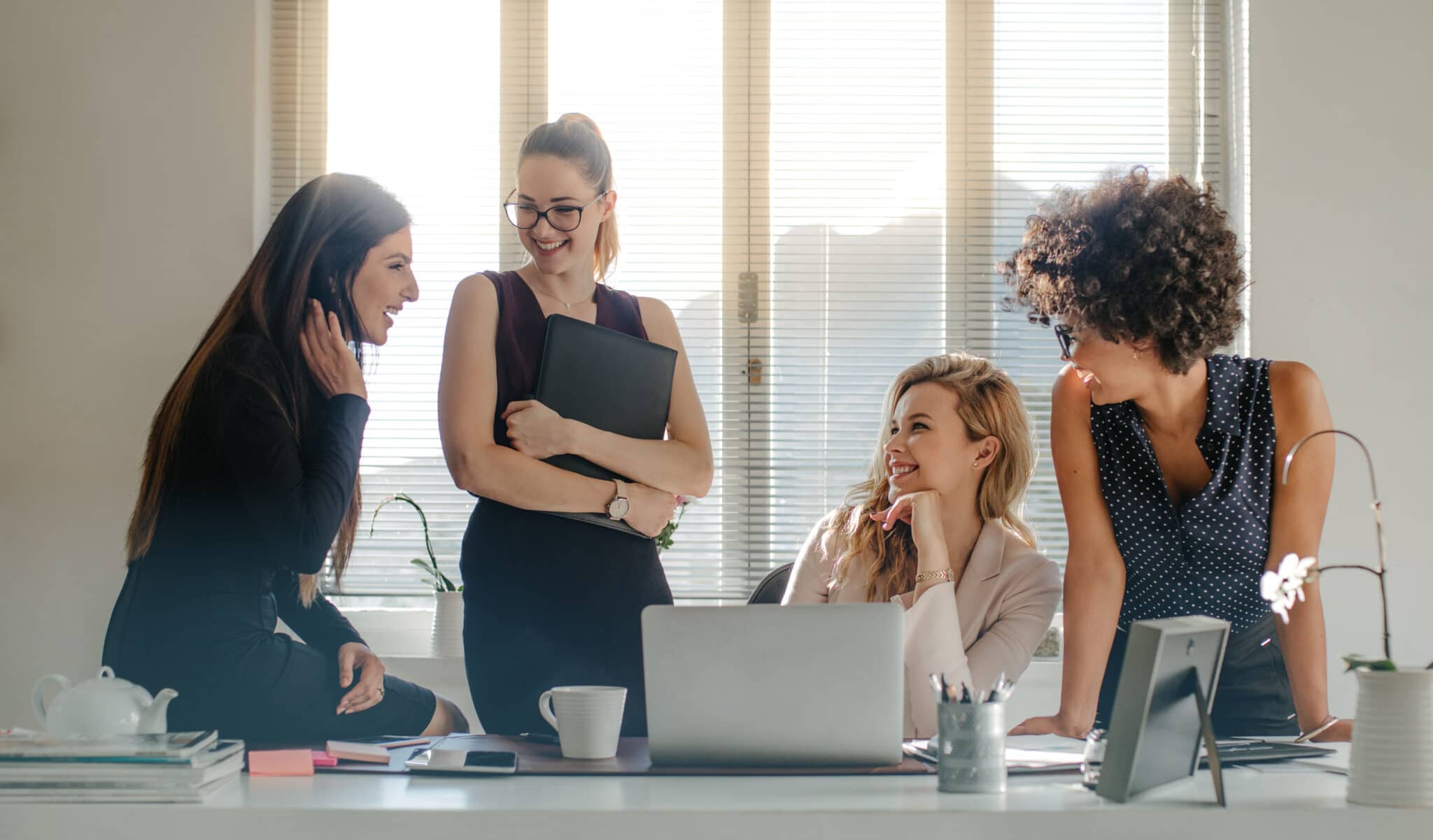 Group of multi-ethnic businesswoman having a casual discussion in office. Group of four women talking during work break in office.