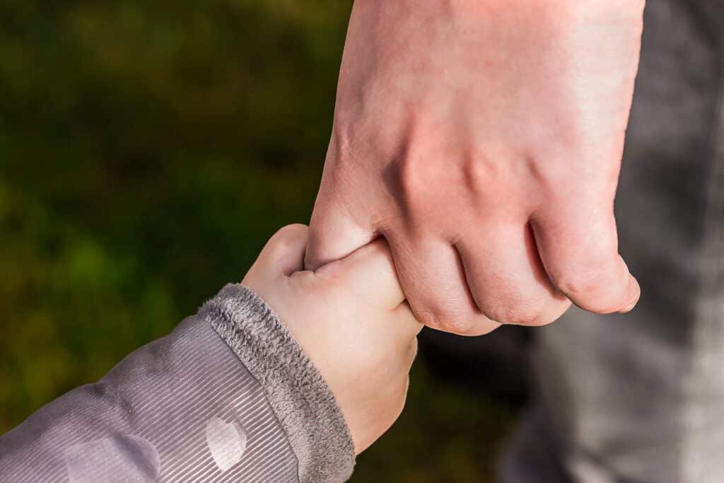 A child holding the hand of an adult