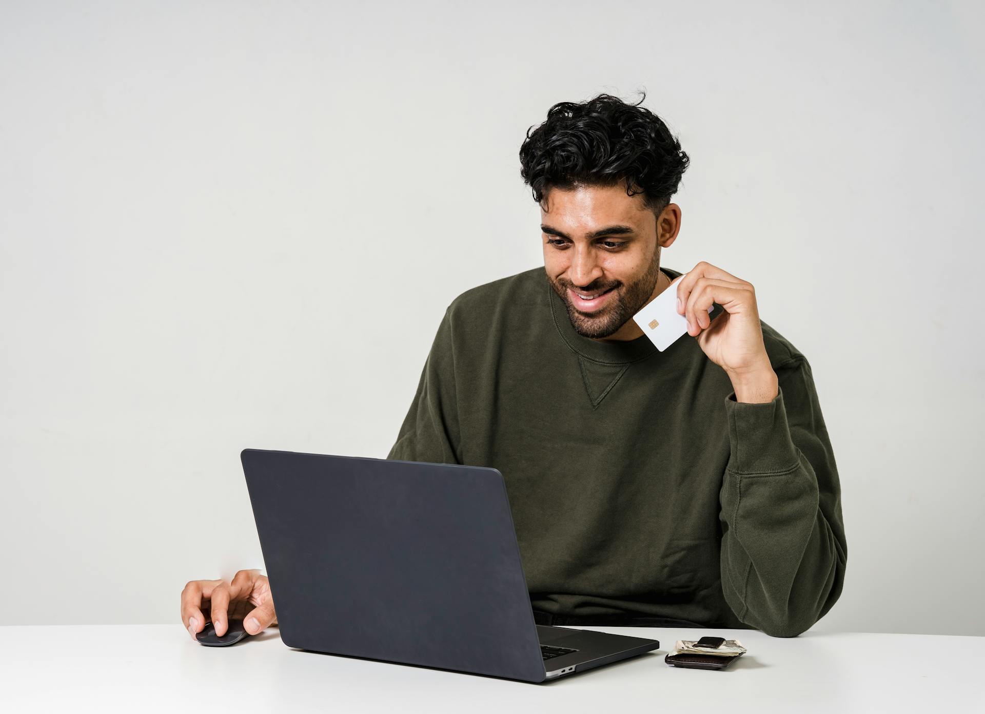 Man in front of a laptop holding a credit card