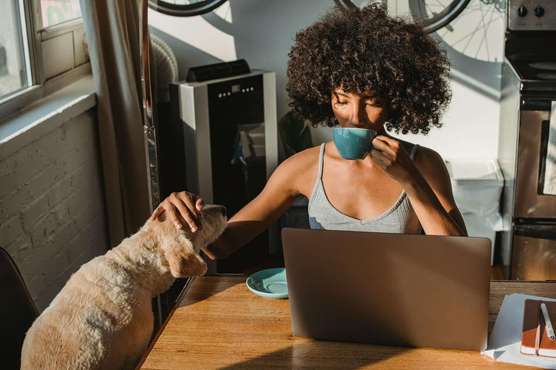 A woman sipping on a cup while working with a dog