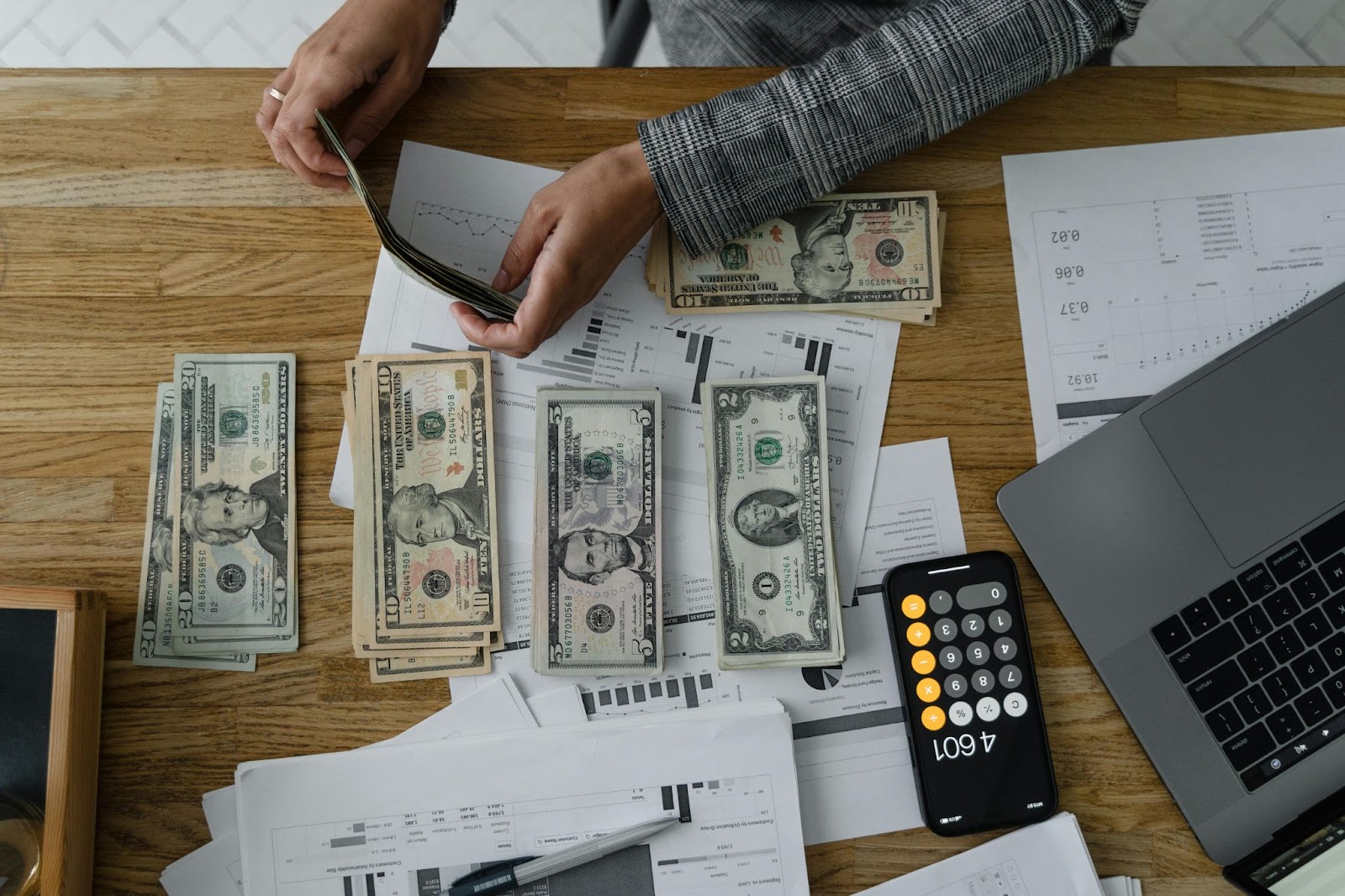 Person counting money on a wooden table