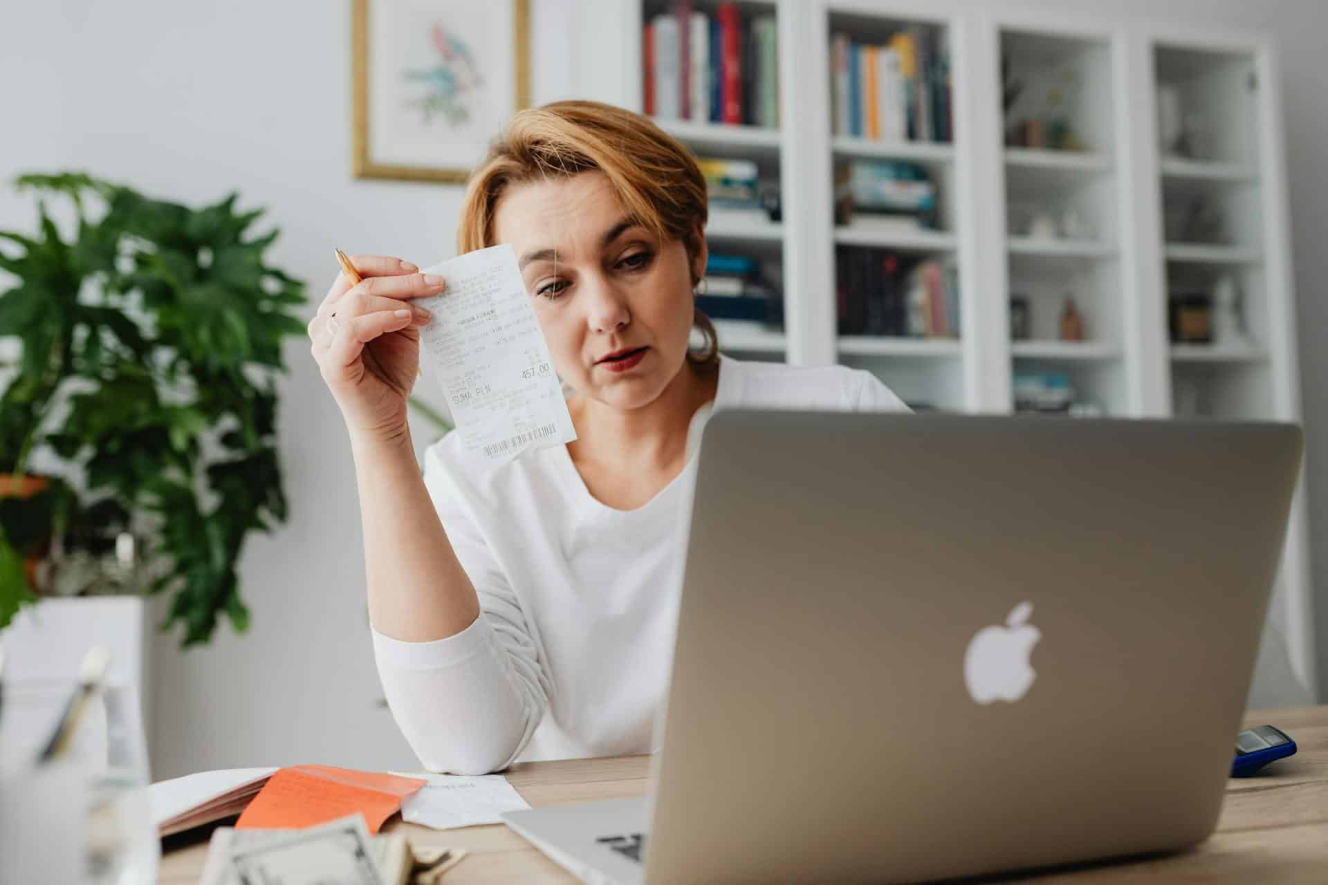 Woman holding a receipt in front of a laptop