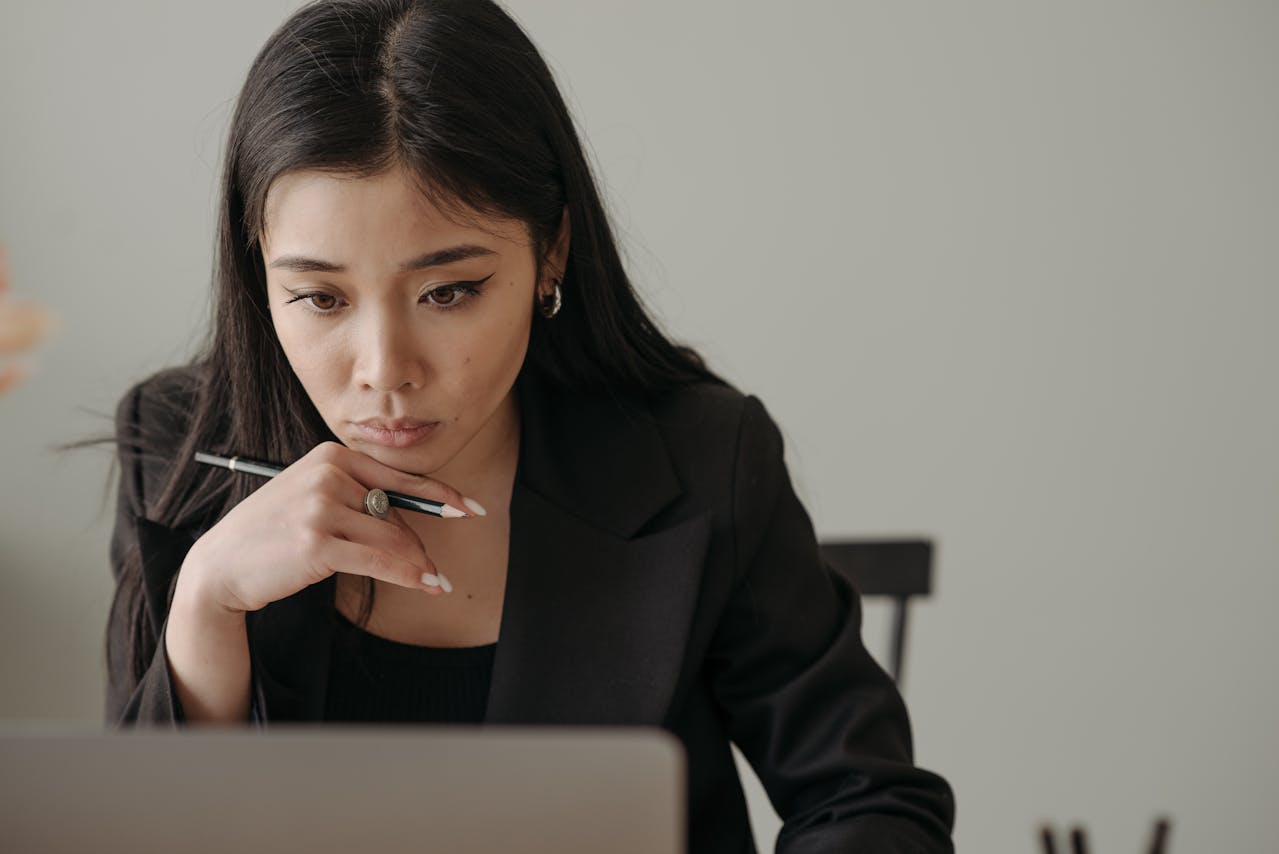 A woman thinking while using her laptop