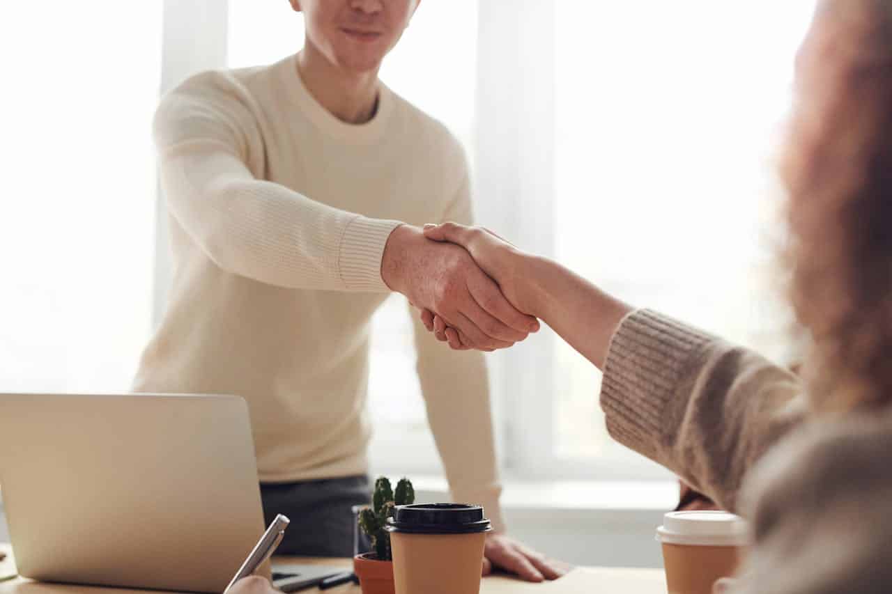 Two people shaking hands in an office setting, suggesting agreement or partnership