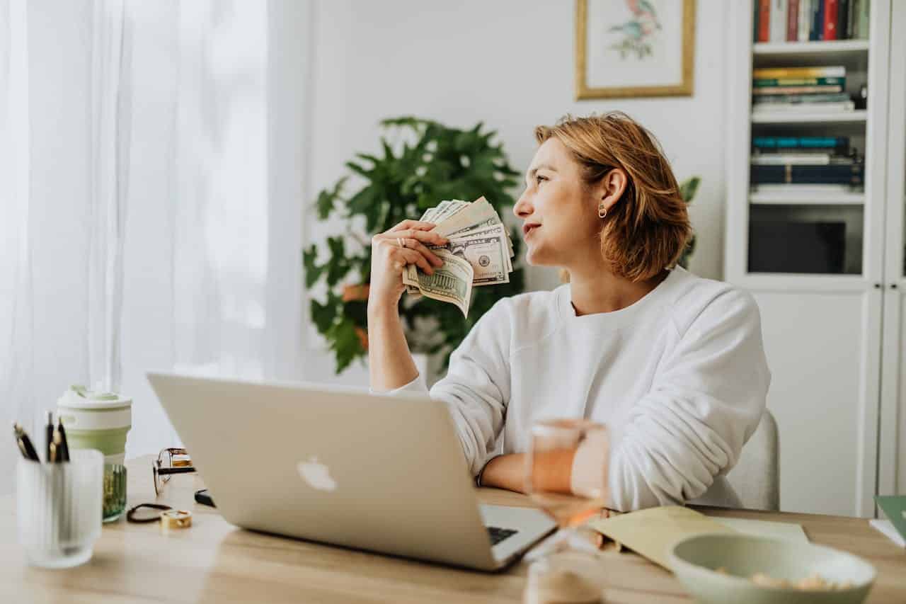 A woman with a laptop holding money