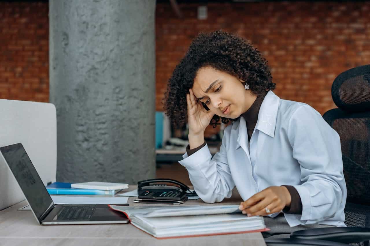 Stressed businesswoman reviewing paperwork at desk