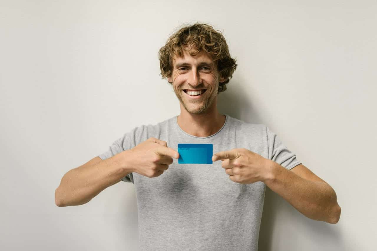 A happy man holding a credit card
