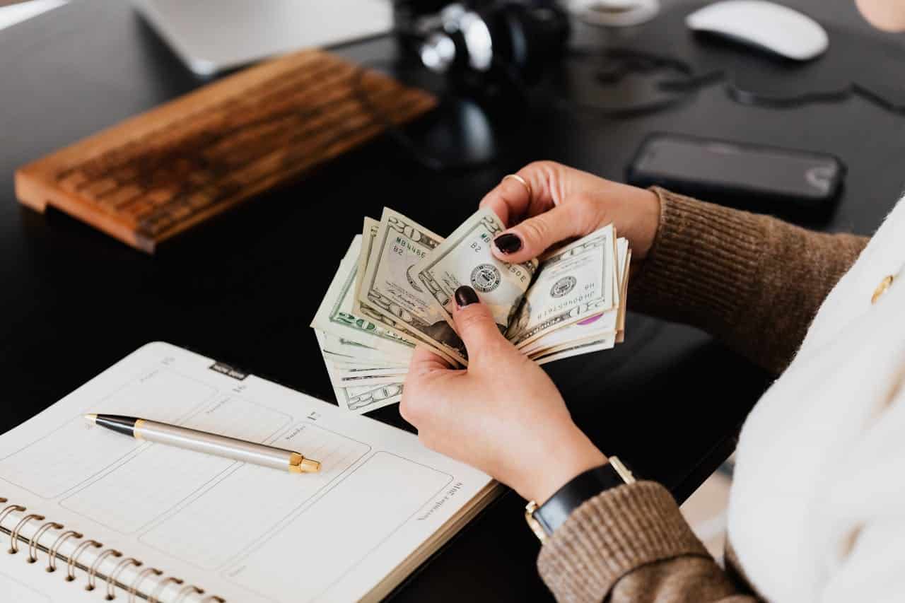 A woman counting twenty-dollar bills