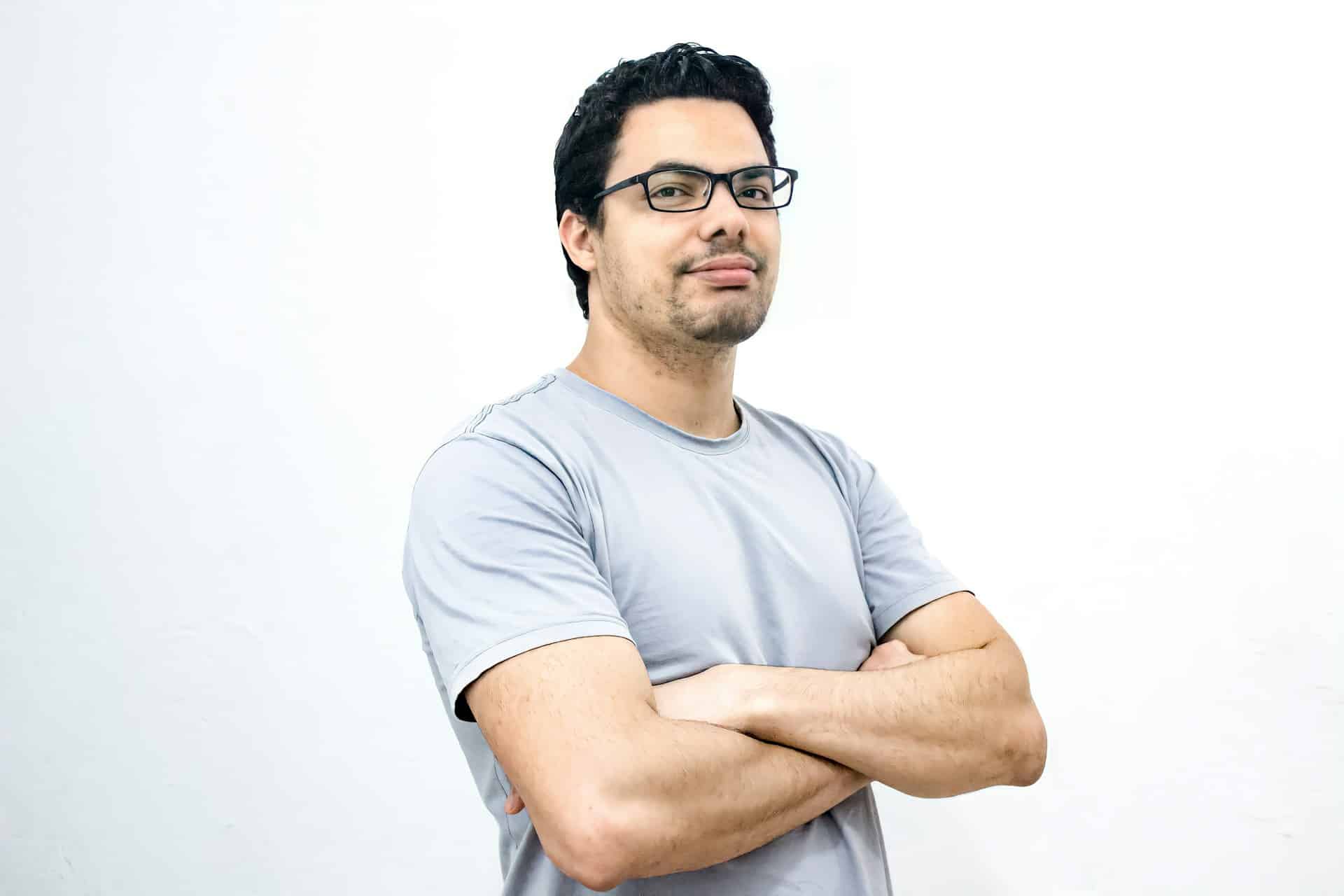 A man with glasses and in a plain gray T-shirt posing for the camera