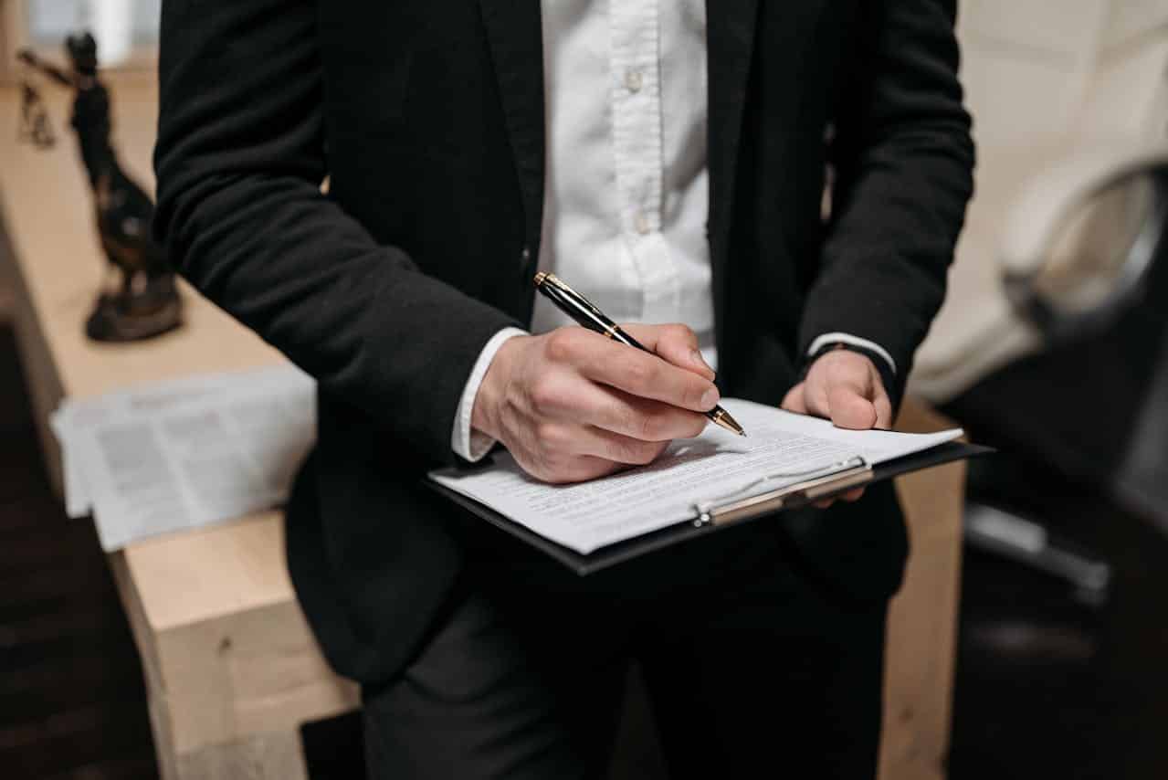 A man signing a contract on a clipboard