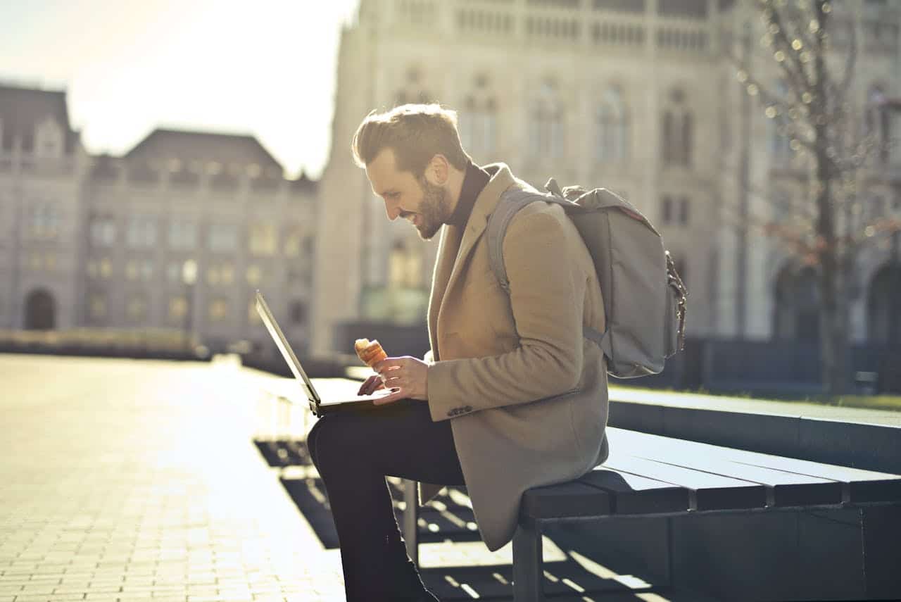 A man with a backpack using his laptop