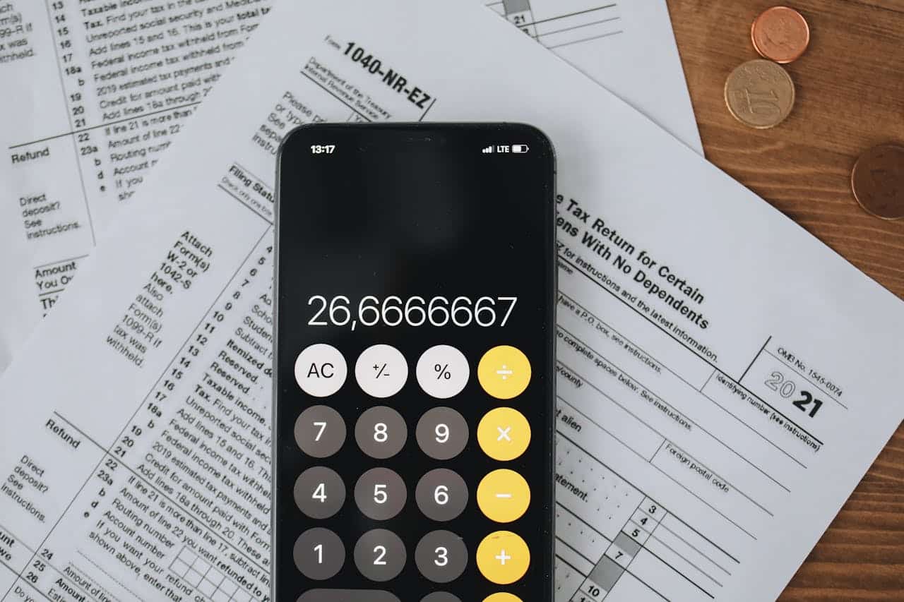 Close-up of a cellphone showing its calculator app on-screen and a tax form