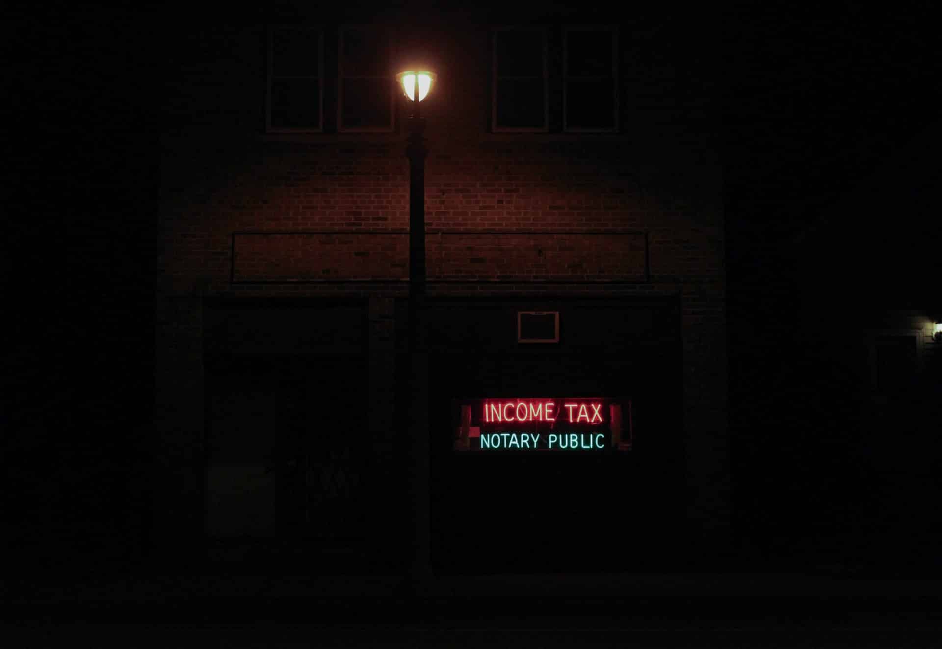 A neon sign that says “Income Tax Notary Public”