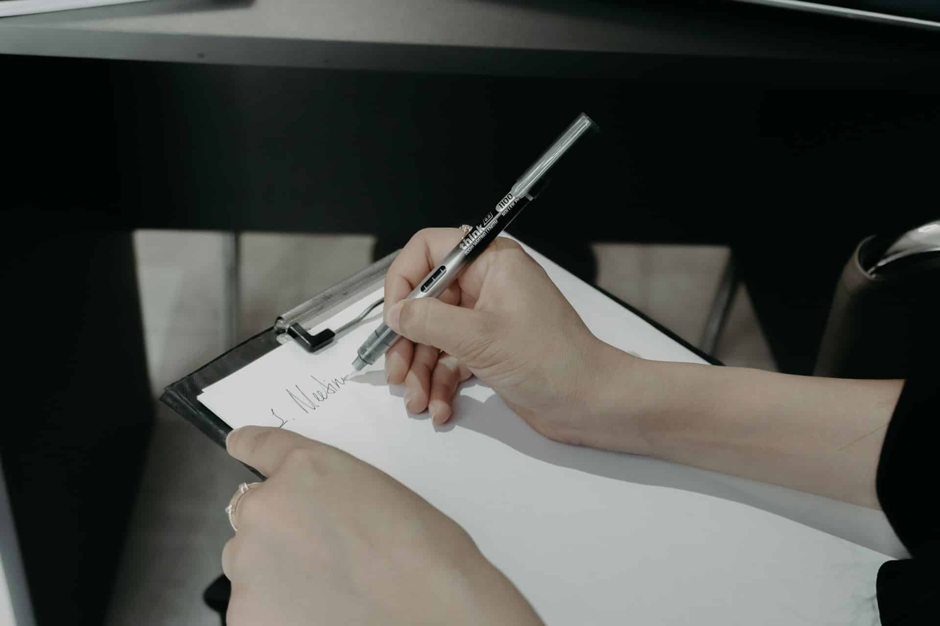Close-up of a person writing on a clipboard
