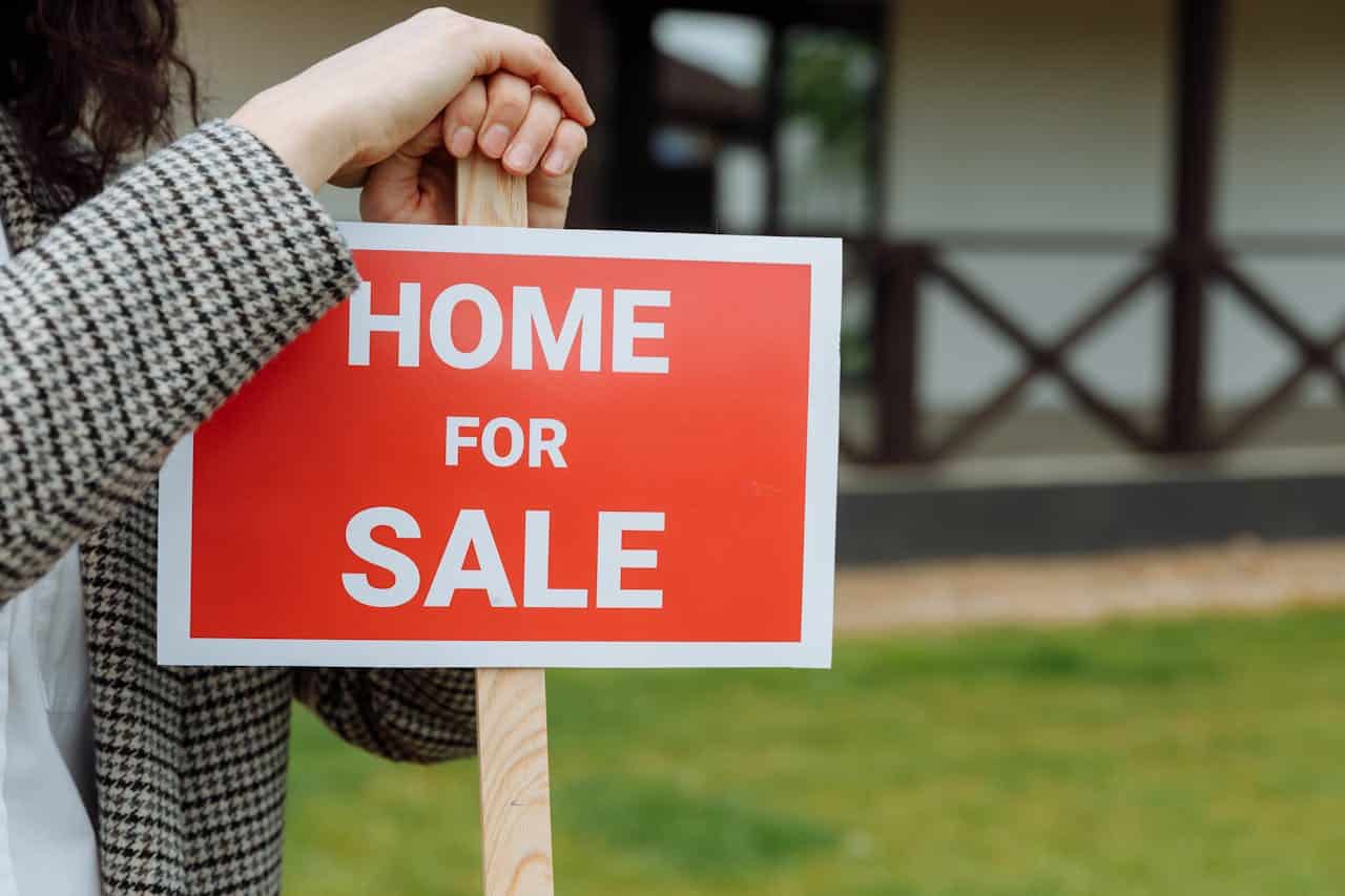Close-up of a female realtor holding a “home for sale” signage