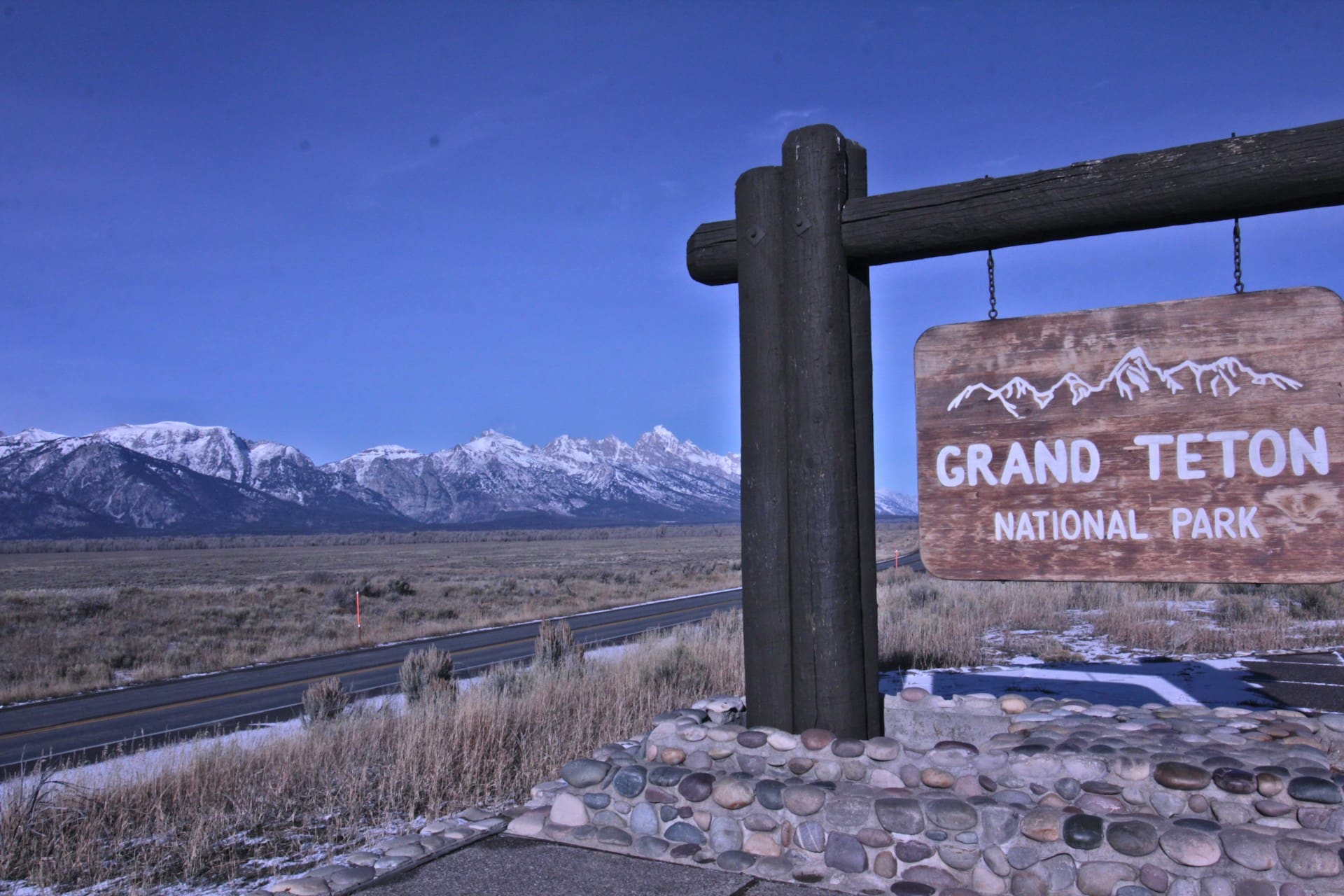 A wooden sign with the name “Grand Teton National Park” painted on it