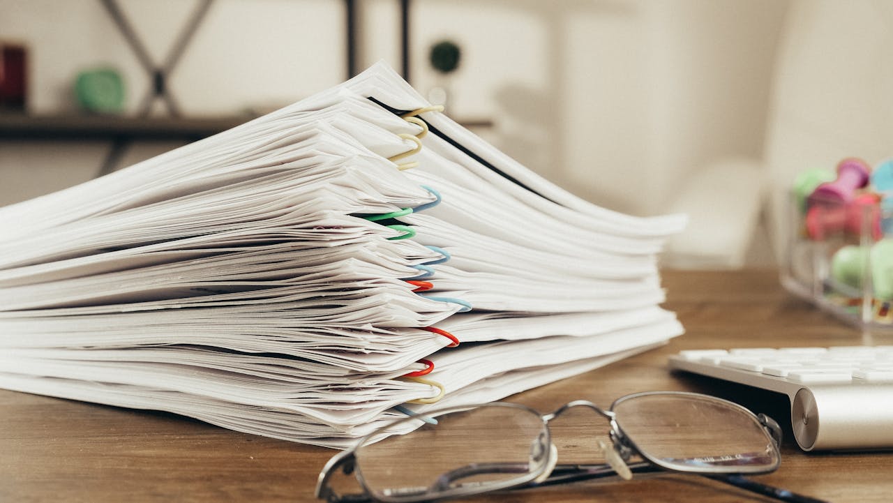 A stack of clipped documents placed on a wooden table