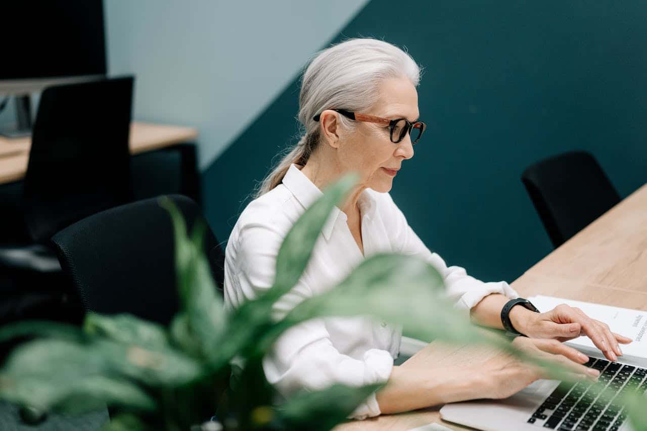 Old woman typing on a laptop