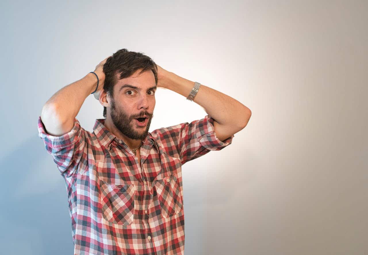 A surprised man holding his head
