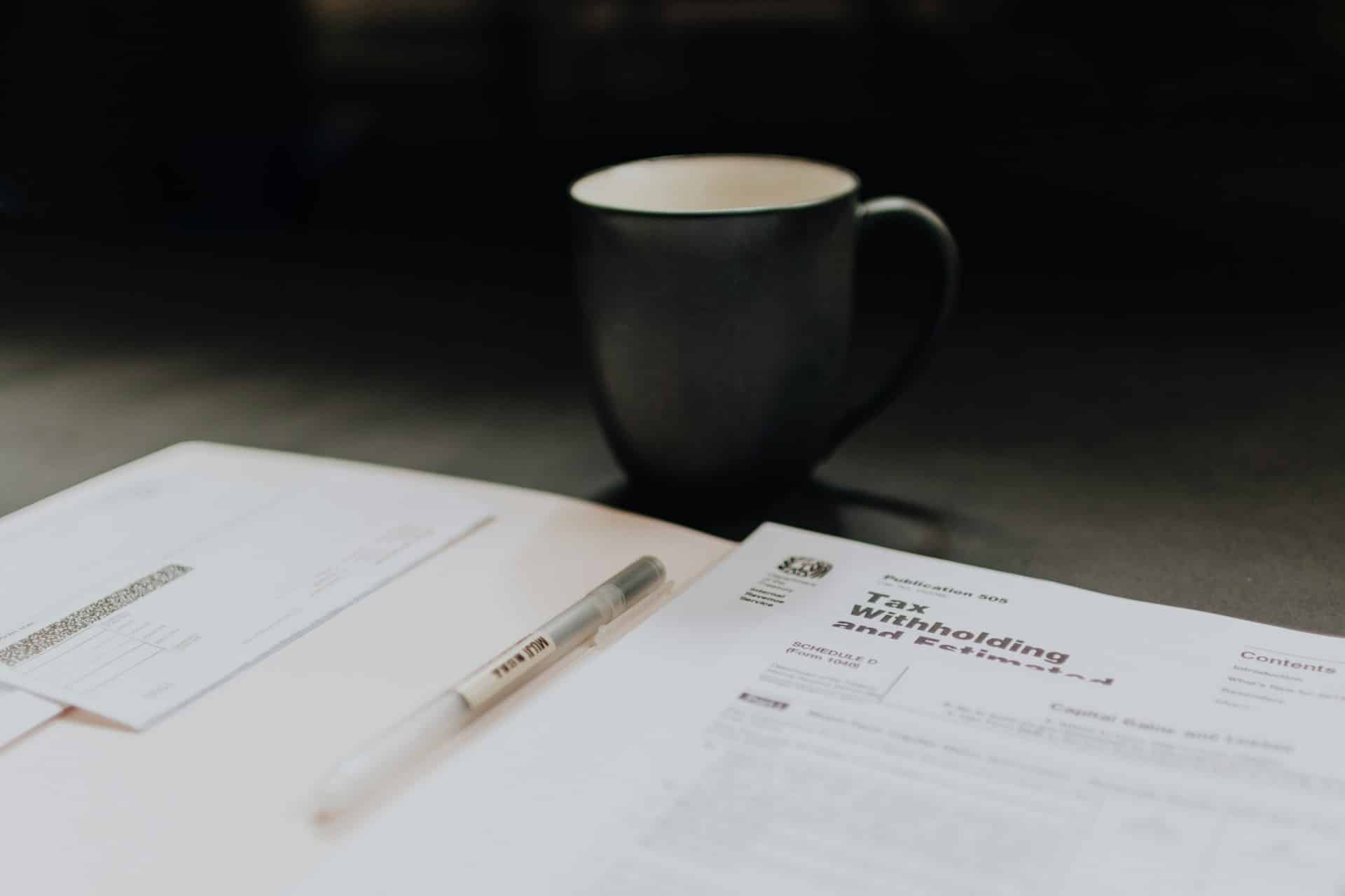 Close-up of a coffee mug placed in front of an open folder