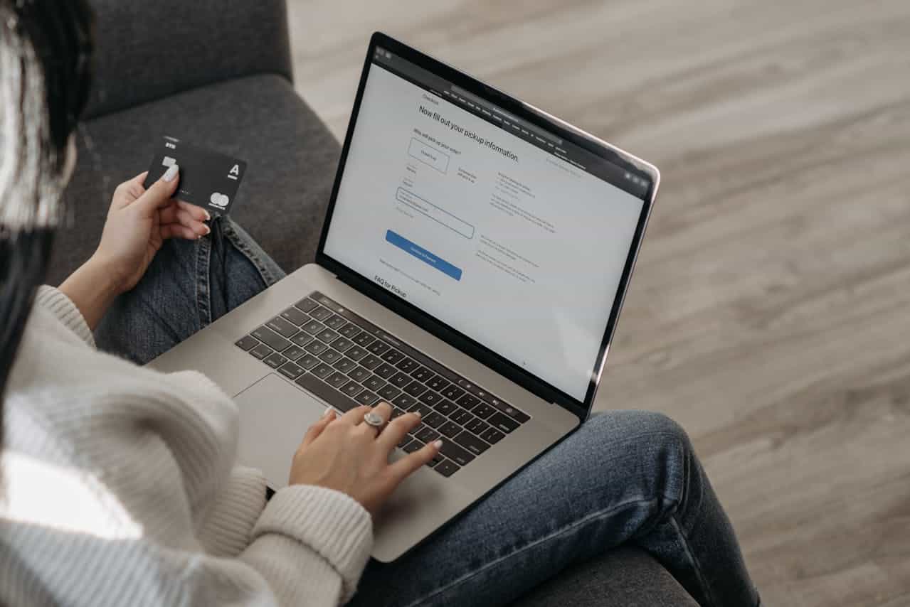 A woman typing on her laptop while holding her credit card