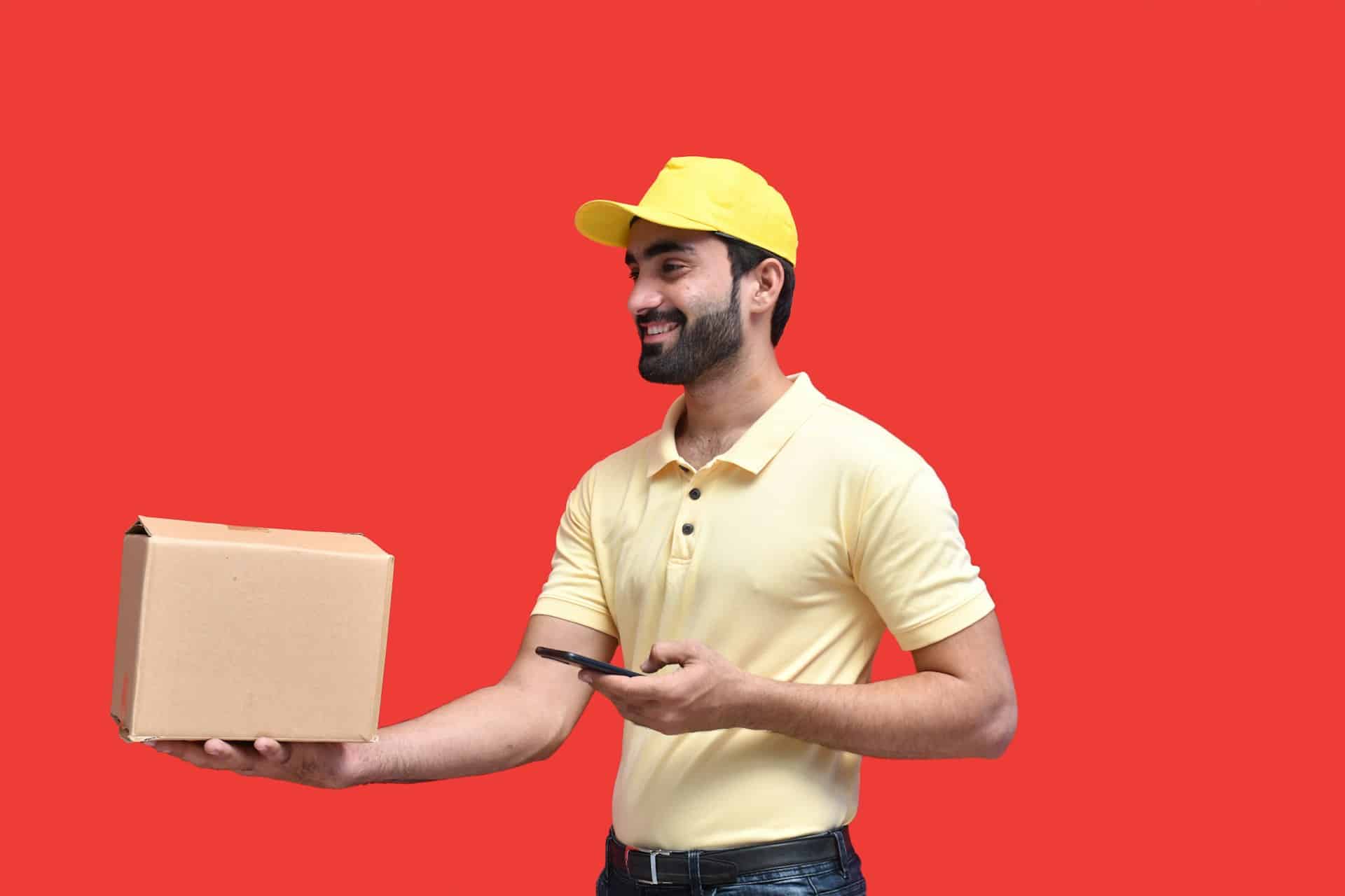 A delivery man holding a small brown box and a smartphone
