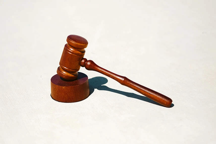 A wooden gavel on a plain surface, symbolizing financial consequences or legal judgment.