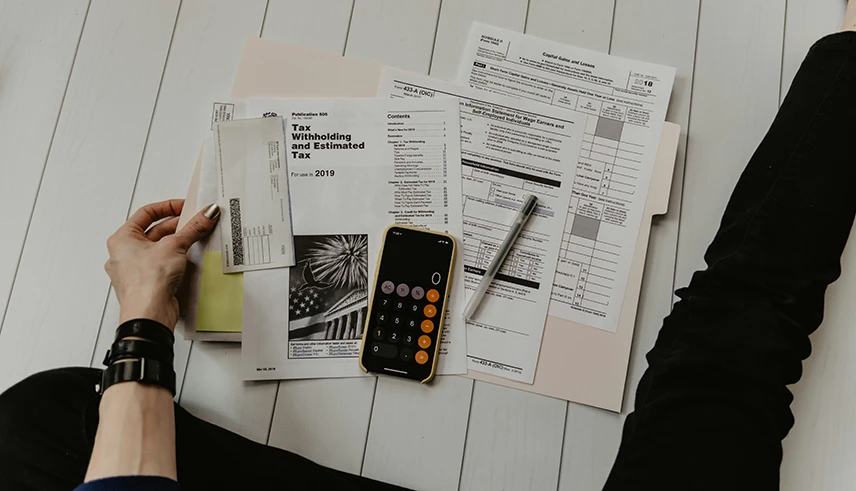 Man reviewing tax on floor with papers and calculator